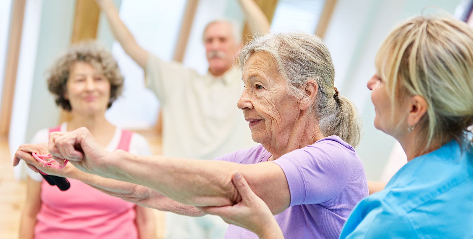 Seniorin wird bei einer bung von einer Trainerin angeleitet