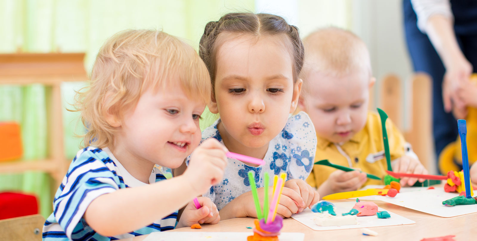 Drei Kinder sitzen an einem Tisch und basteln