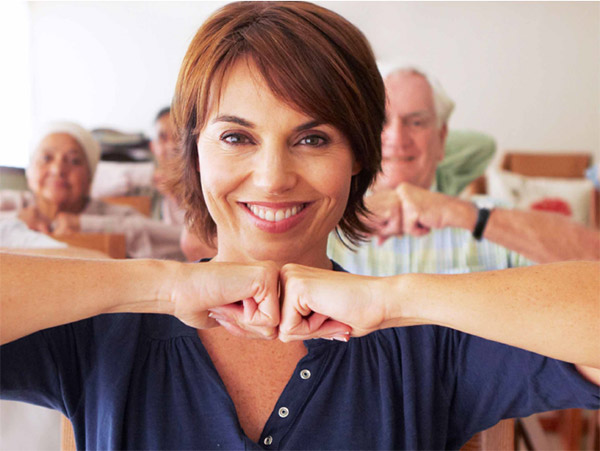 Halbportrt - junge Frau schaut lachend in die Kamera, ihre Arme hlt sie waagerecht und ihre Hnde bilden Fuste und treffen sich vor ihr.